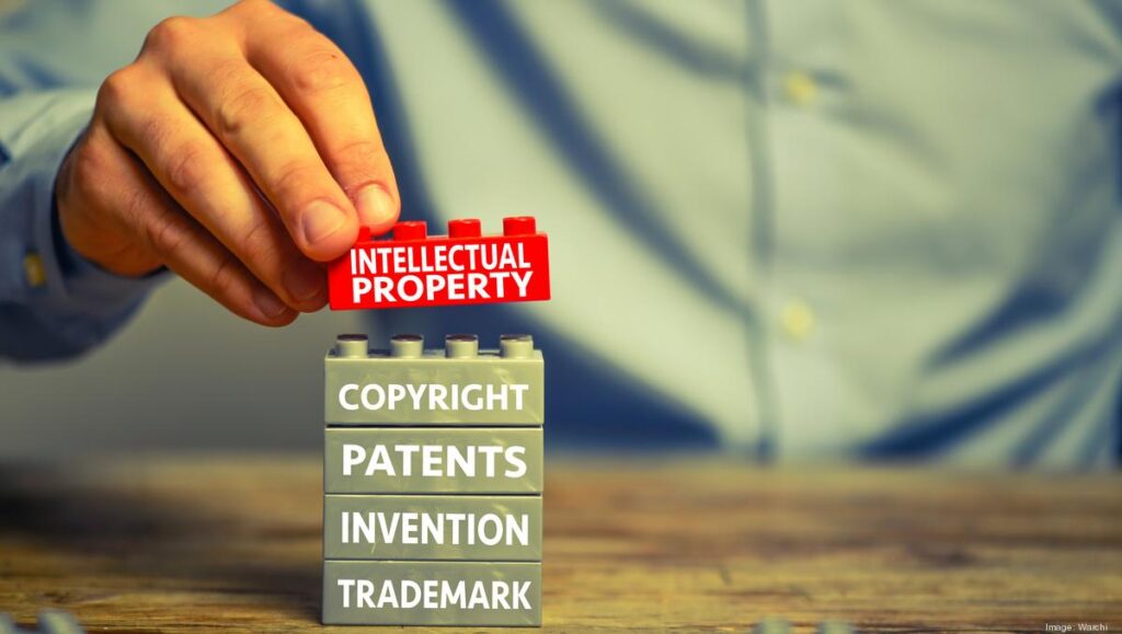 In the background, there are various icons representing intellectual property assets, such as patents, trademarks, and copyrights. The image represents the key concepts of assessing intellectual property rights in startup investing, highlighting the importance of considering these assets when evaluating investment opportunities.